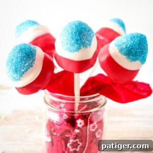 Red, white, and blue covered strawberries on sticks in a mason jar.