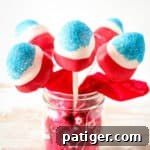 Red, white, and blue covered strawberries on sticks in a mason jar.