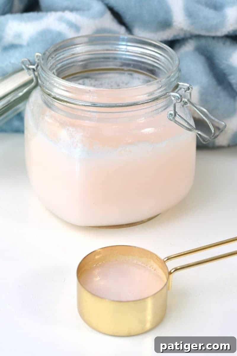 A jar of finished DIY fabric softener with a wooden scoop, ready for use in laundry.