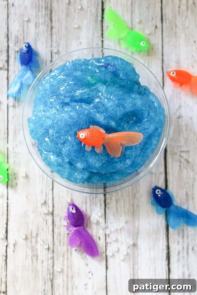 Vibrant blue and glittery borax-free ocean slime with plastic fish, perfect for summer sensory play.