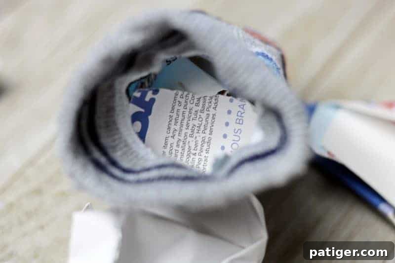 Step 1: Filling a baby sock with crumpled paper for a homemade cat toy.