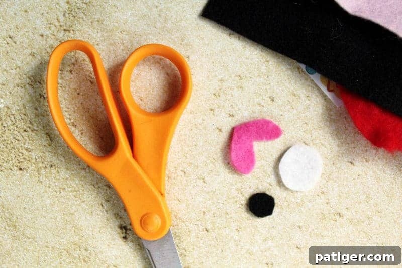 Playful Paper Plate Fish Creations 5 Close-up step-by-step image showing how to cut out felt pieces for the fish's pink lips, white eye base, and small black pupil.