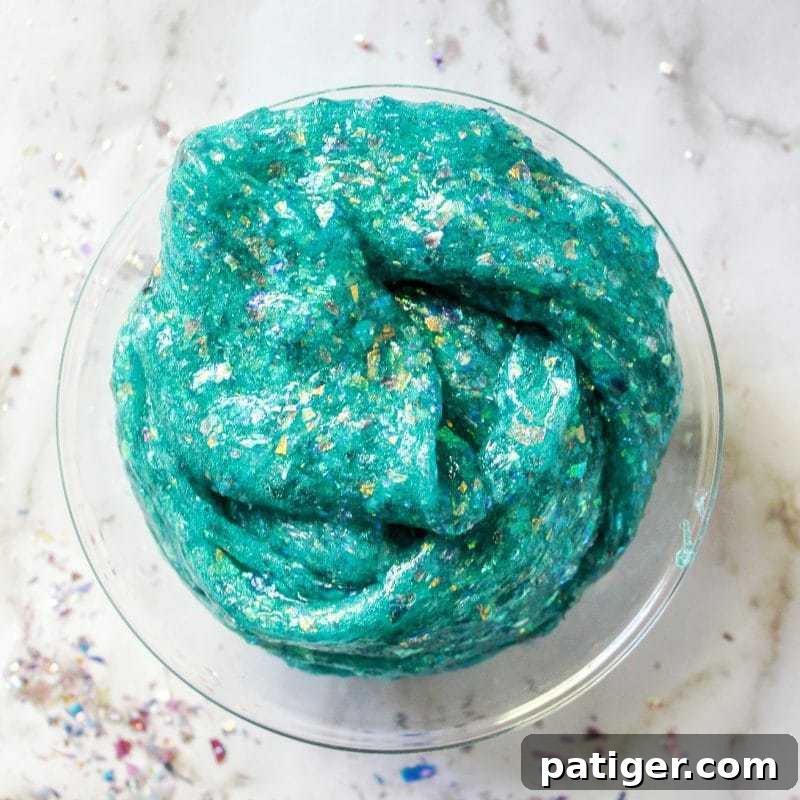 Borax-free sparkly mermaid slime in a child's hands, perfect for a mermaid party activity.