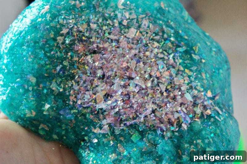Adding more glitter to the completed borax-free mermaid slime for extra sparkle.