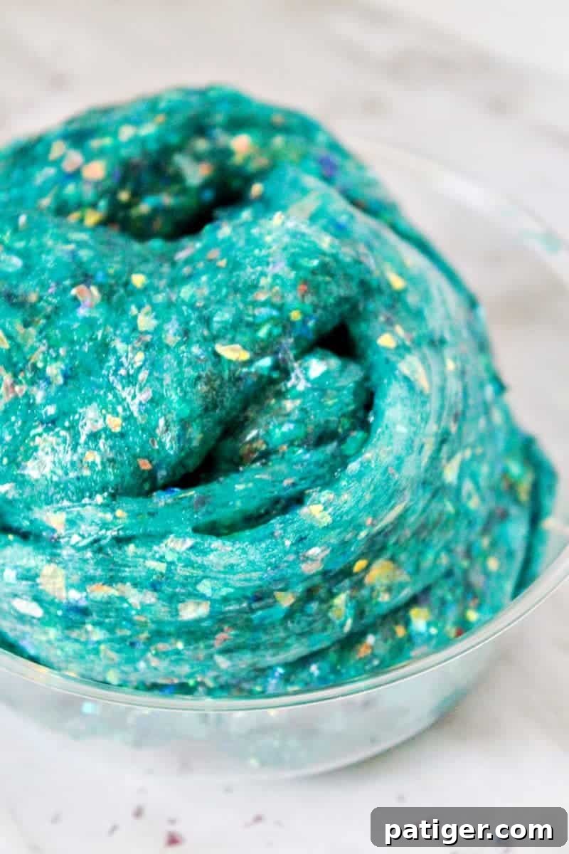 Child's hands stretching sparkling borax-free mermaid slime, displaying its glittery texture.