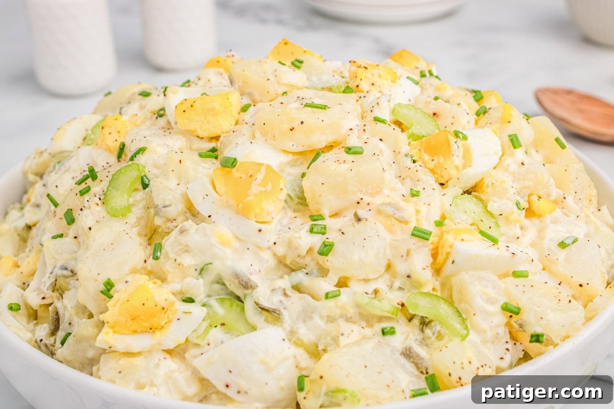Creamy potato salad with chopped eggs and celery, garnished with fresh parsley.