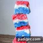 A red, white, and blue marshmallow creme fudge recipe made with marshmallow creme, evaporated milk, white chocolate chips, sugar, butter, and food coloring.