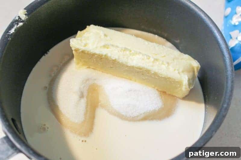 The initial stage of making red, white, and blue marshmallow creme fudge, showing sugar, butter, and evaporated milk heating in a saucepan.