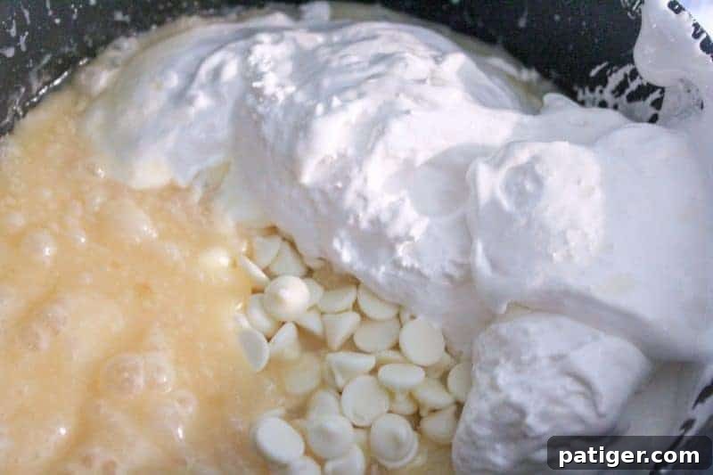 White chocolate chips and marshmallow creme being added to the hot fudge base for a smooth and creamy red, white, and blue fudge.