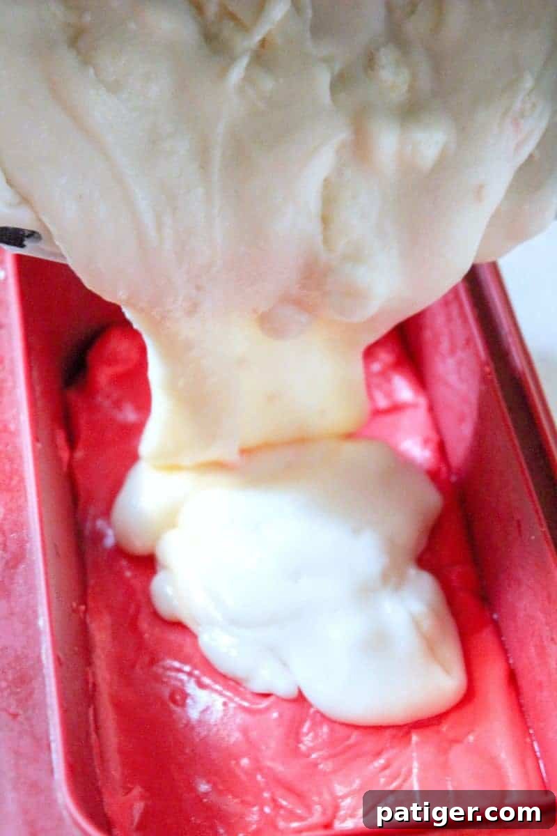 Layering the red, white, and blue fudge mixture into a prepared baking pan, one color at a time, to create a distinct patriotic striped effect.