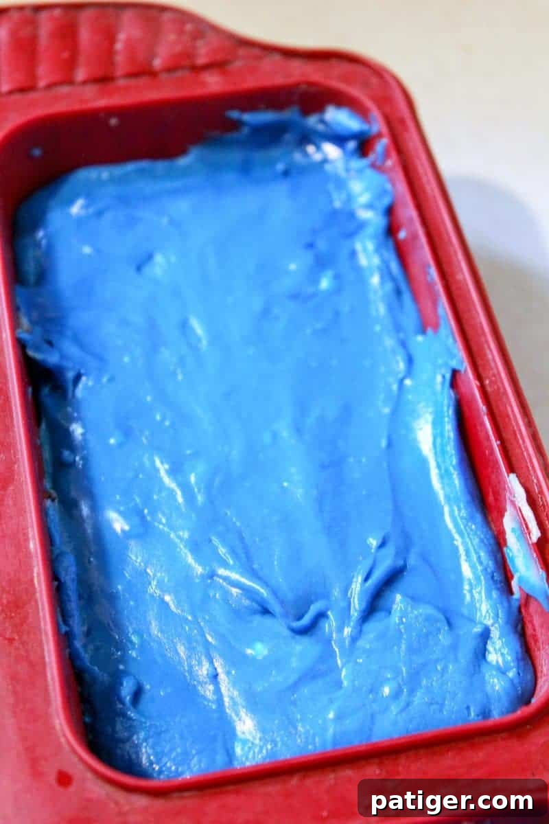 The red, white, and blue fudge layers neatly poured into the pan, demonstrating the patriotic colors before chilling.