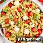Caprese Pasta Salad with rotini pasta, mozzarella balls, fresh basil, and tomatoes in a large bowl