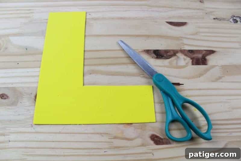 Tracing the cut-out letter L template onto a sheet of colorful craft foam, preparing for the next step of cutting the letter shape.