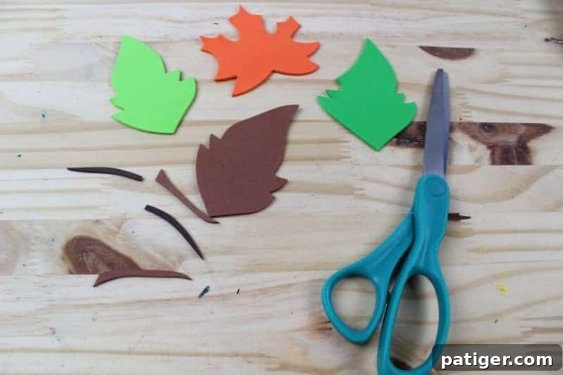 Cutting out leaf shapes from various colors of craft foam using a printable template, preparing them to be attached to the letter L.