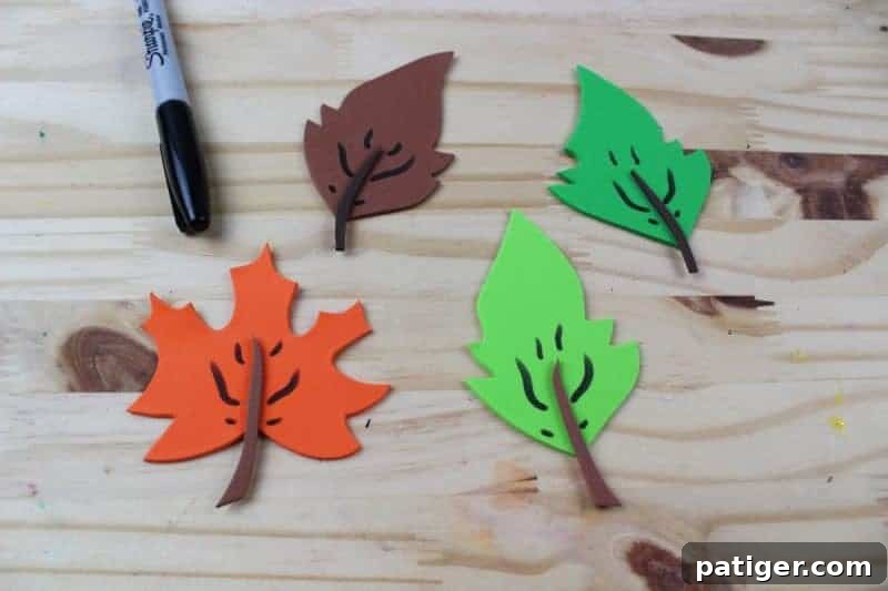 Using a black marker to draw delicate veins on the craft foam leaves, enhancing their natural appearance before attaching them to the letter L.