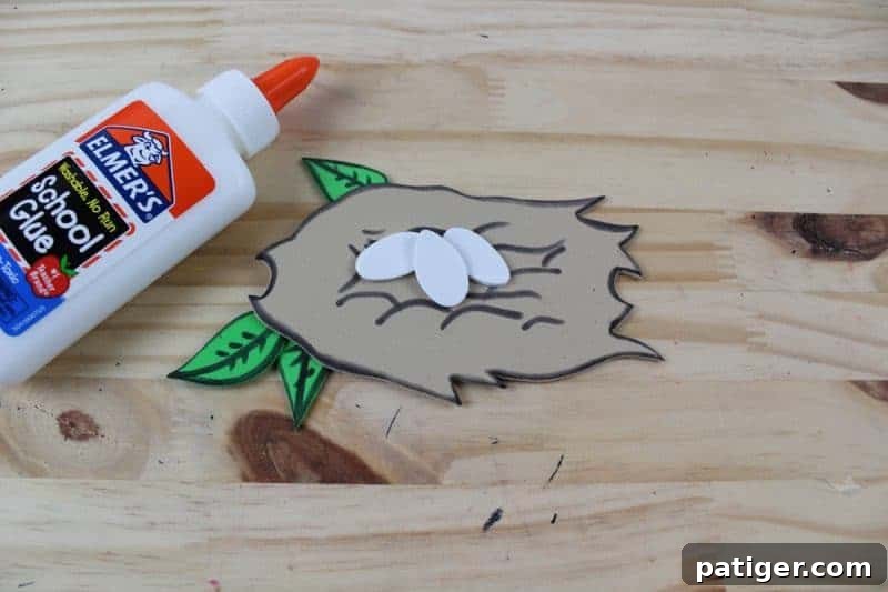 Nifty Nests Printable Letter N Craft 8 Step 6 of the Letter N craft: Gluing the pre-cut eggs and leaves onto the detailed nest shape, creating the core elements of the nest before attaching it to the letter N.