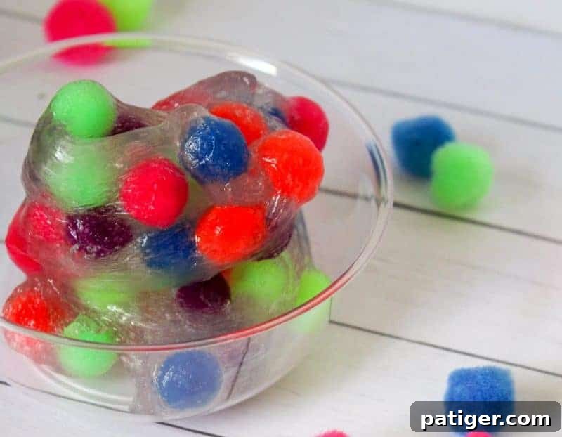 Brightly colored pom poms suspended in clear slime for a fun sensory activity.