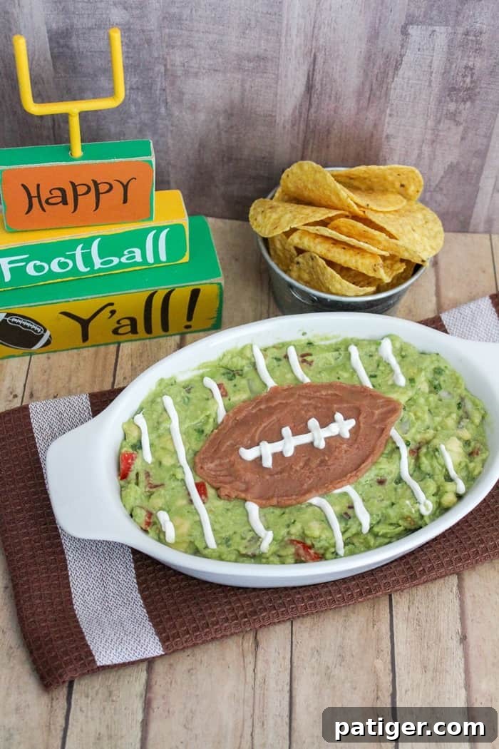 Fresh homemade guacamole, a vibrant green dip, shown with an assortment of fresh ingredients including ripe avocados, red onion, cilantro, and tomato, ready for game day.