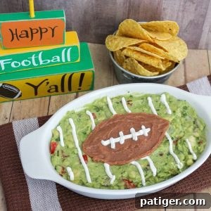 A festive game day guacamole recipe, artfully decorated to resemble a football field, served with crunchy tortilla chips.