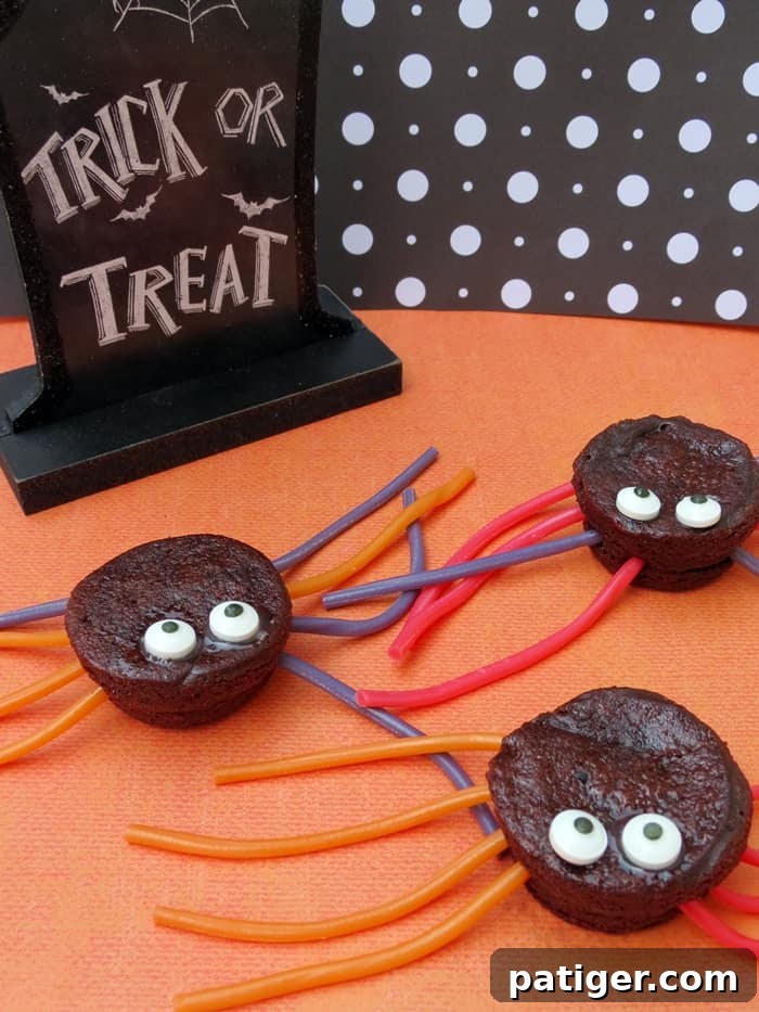 Adorable spider brownies made from brownie bites, candy eyes, and licorice laces arranged on a spooky Halloween platter.