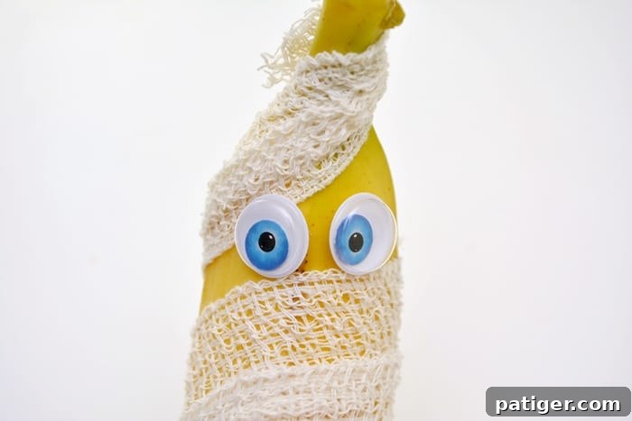 A finished mummy banana with googly eyes, wrapped in gauze for a Halloween snack