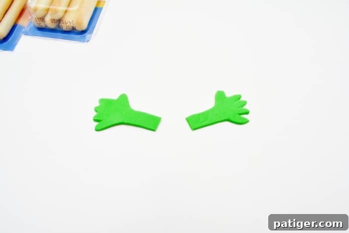 Close-up image of a Halloween monster cheese and cracker snack with green foam arms