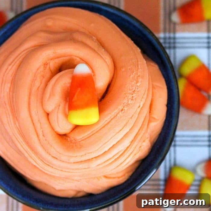 Close-up of stretchy, edible candy corn slime being pulled apart by hands, showcasing its unique texture