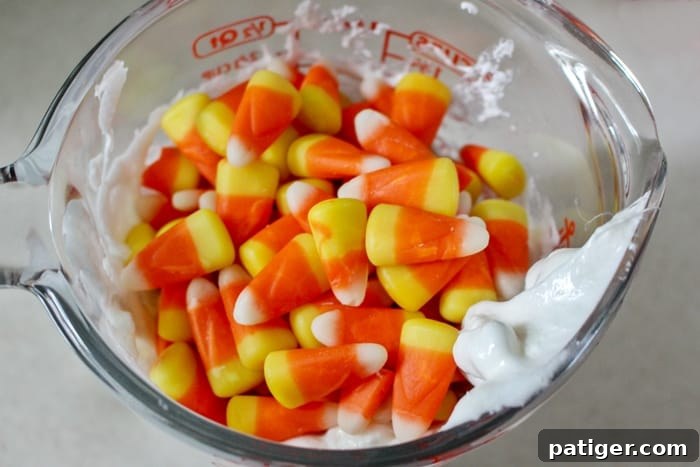 A child's hands exploring a batch of homemade edible candy corn slime on a wooden table