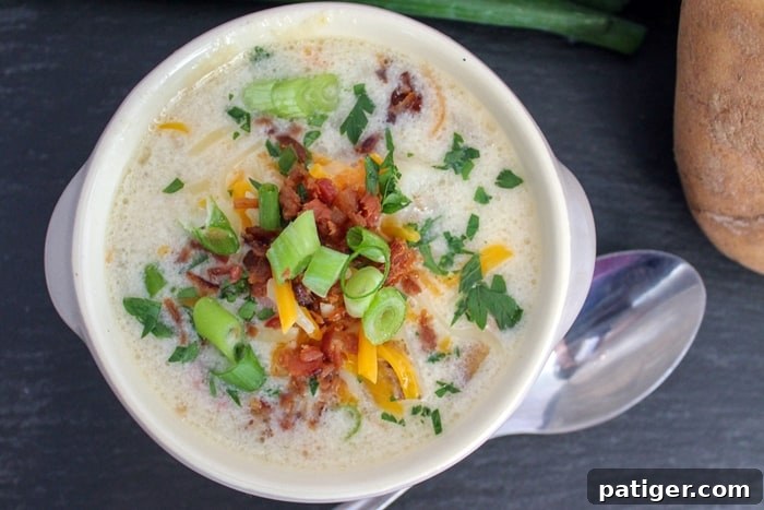 A bowl of lusciously creamy Instant Pot potato soup, garnished with vibrant green scallions and crispy bacon bits, ready to be enjoyed.