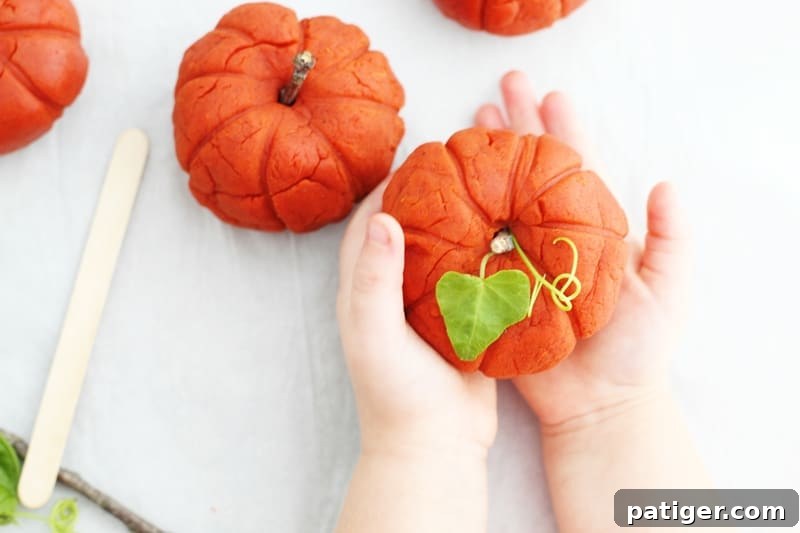 Sensory Pumpkin Spice Playdough 11 Child proudly holding a pumpkin-shaped pumpkin spice playdough creation