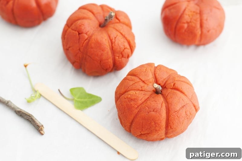 Sensory Pumpkin Spice Playdough 10 Child adding a stick to a pumpkin-shaped playdough for decoration