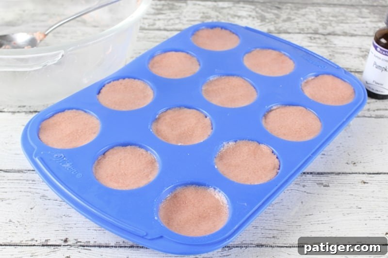 A silicone mini muffin pan neatly filled with the pumpkin spice bath bomb mixture, ready for drying.
