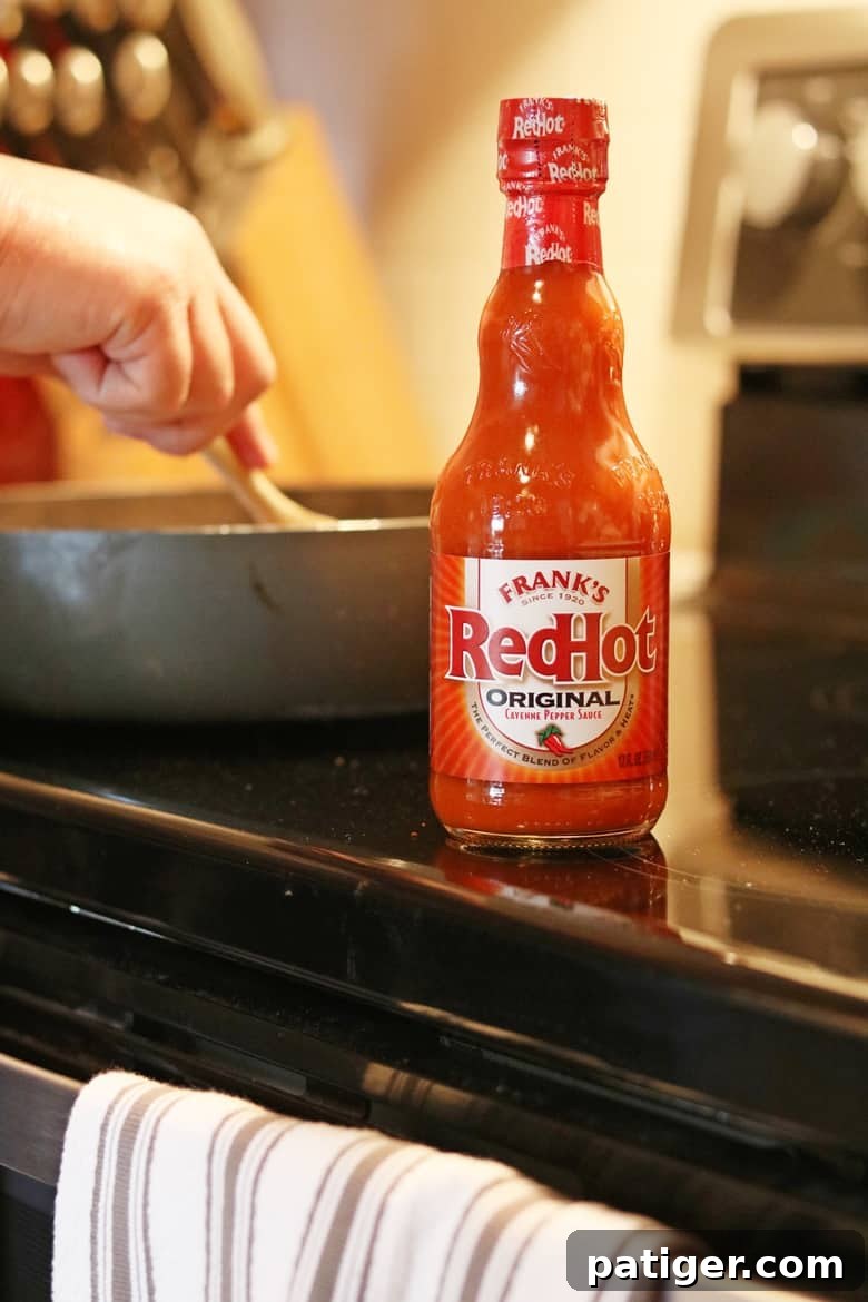 Frank's RedHot Sauce being mixed into sizzling ground beef in a skillet, creating a flavorful base for spicy nachos or tacos.