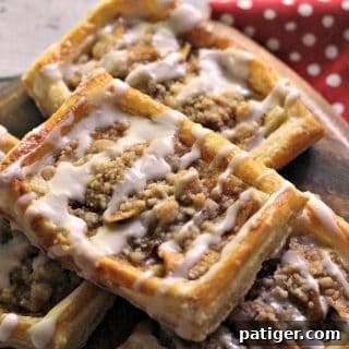 A freshly baked apple danish recipe with a delicious crumb topping and a delicate drizzle of icing, presented beautifully on a platter.