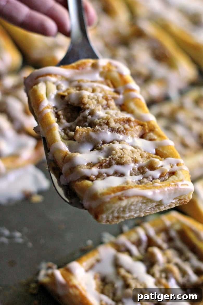 An overhead shot showcasing multiple perfectly baked apple danishes, each featuring a delicious crumb topping and a beautiful drizzle of icing. These tasty apple crumb danishes are ideal for a sweet breakfast or an elegant brunch option.