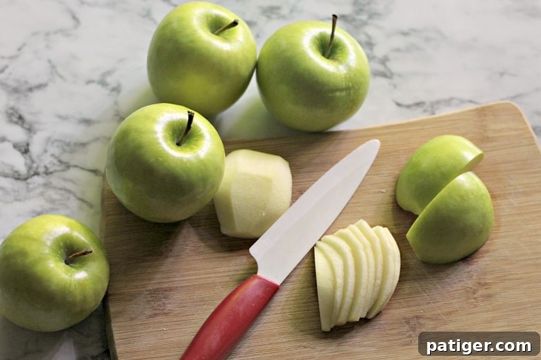 Fresh green apples being thinly sliced on a wooden cutting board, ready for the apple danish recipe.