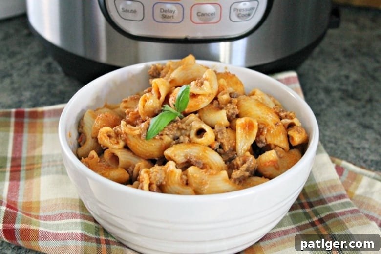 Cheesy Hamburger Casserole in a white bowl in front of an Instant Pot, perfectly golden and bubbly
