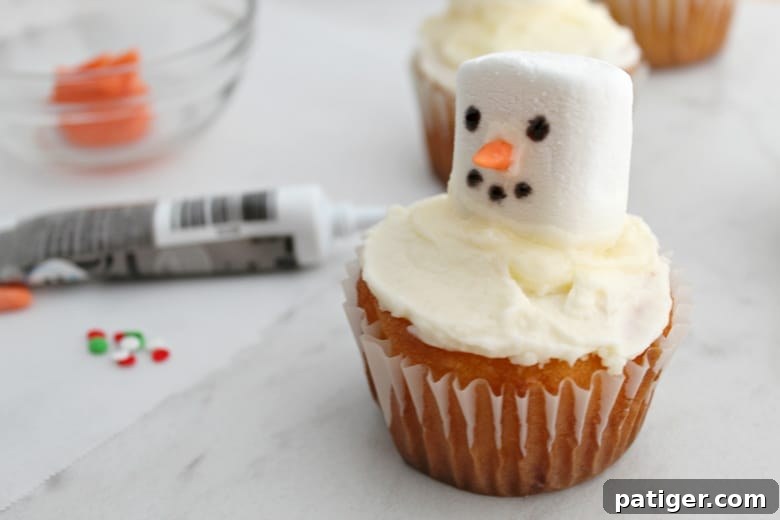 In process picture of snowman cupcake with nose, eyes and mouth completed
