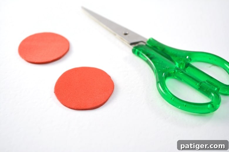 Handmade Wine Cork Candle Ornaments 4 Two perfectly cut circles of vibrant red craft foam positioned alongside a pair of sharp green scissors, ready for crafting.