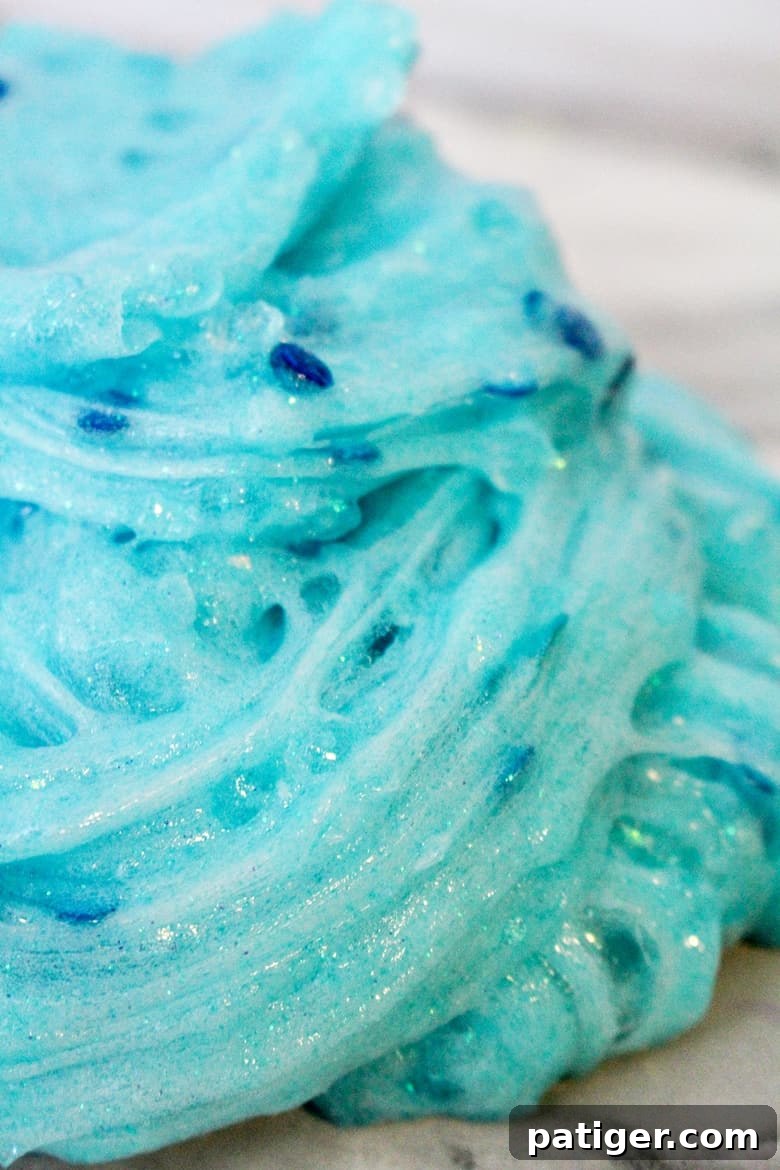 Close-up of sparkling blue Frozen slime on a white marble table.