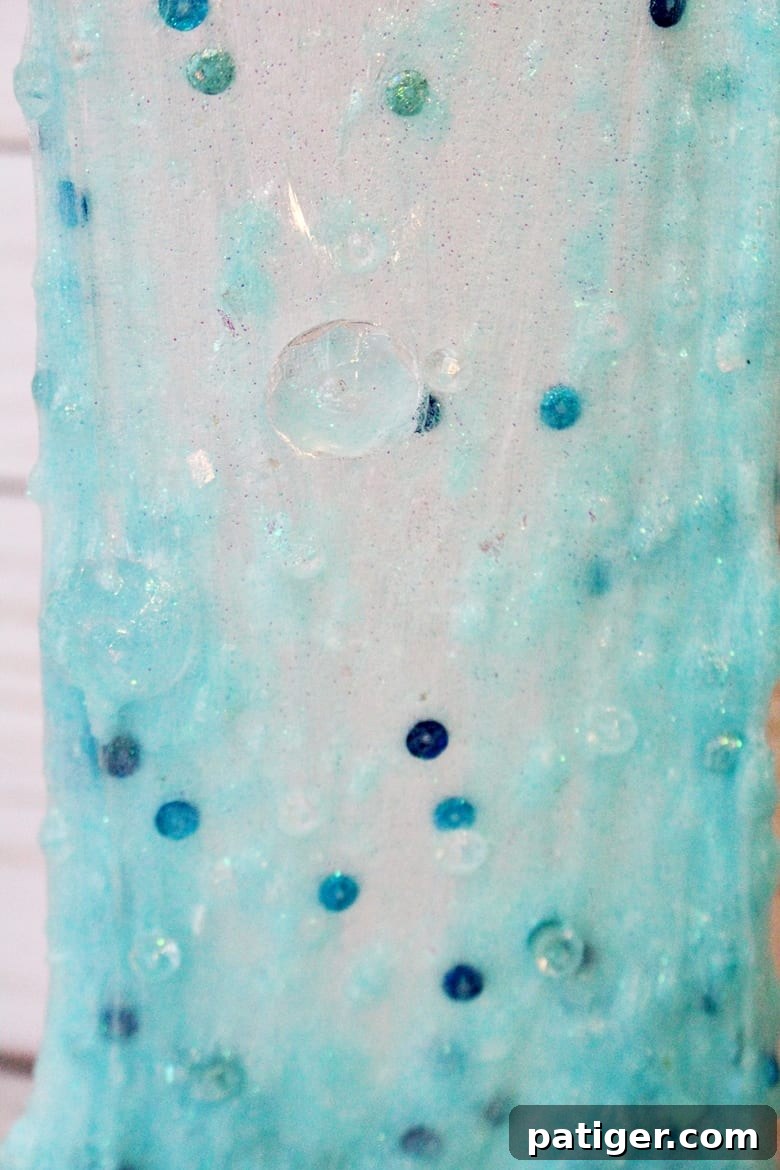 Another close-up of sparkling blue Frozen slime with snowflake charms and glitter, suitable for Disney's Frozen theme.