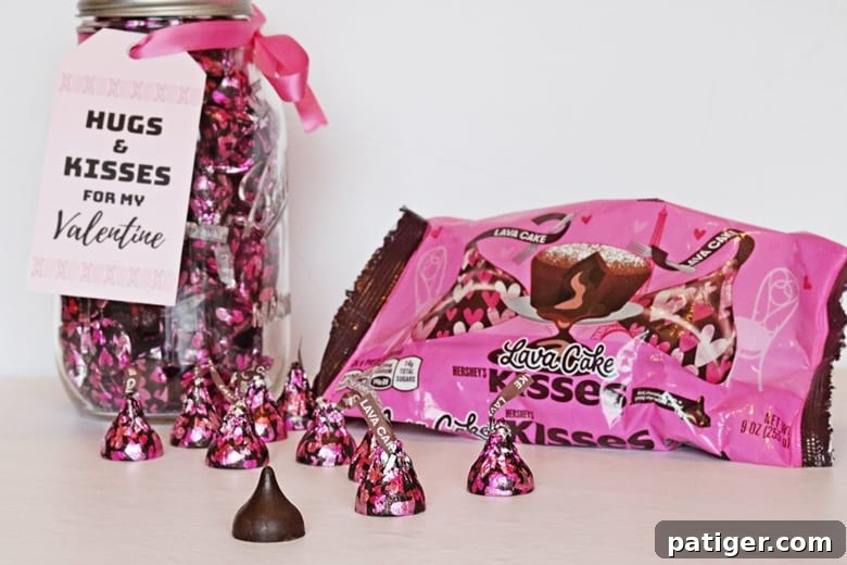 Close-up of a mason jar filled with Hershey Kisses, featuring a "hugs and kisses" themed printable Valentine label.