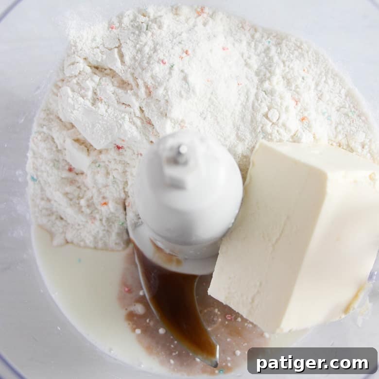 Dry funfetti cake mix, softened cream cheese, milk, and vanilla extract are precisely measured and added to a food processor bowl for blending.