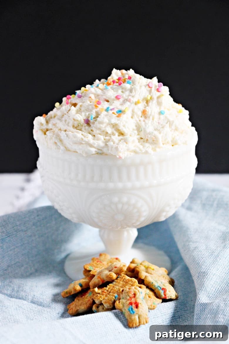 A beautifully presented Funfetti cake batter dip served in a large white bowl, surrounded by a generous selection of teddy grahams and other dippers, inviting guests to indulge.
