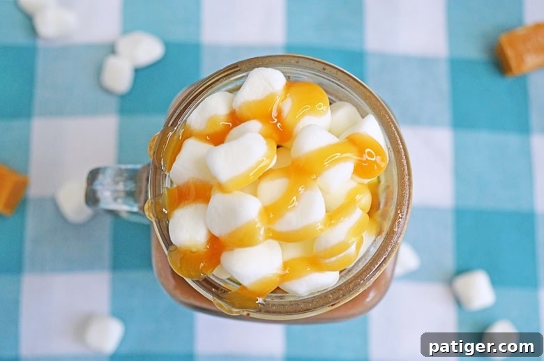 A steaming mug of rich and creamy salted caramel hot chocolate, garnished with whipped cream and a drizzle of caramel sauce. Made easily in a slow cooker.