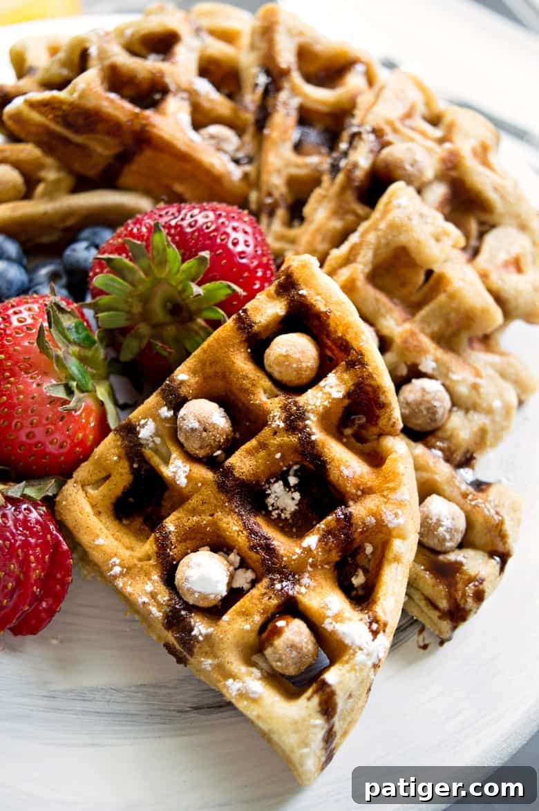 A serving of Reese's Puffs Cereal Waffles, quartered and artfully arranged on a white plate, garnished with fresh berries, a drizzle of chocolate syrup, and a sprinkle of extra Reese's Puffs for added crunch and flavor.