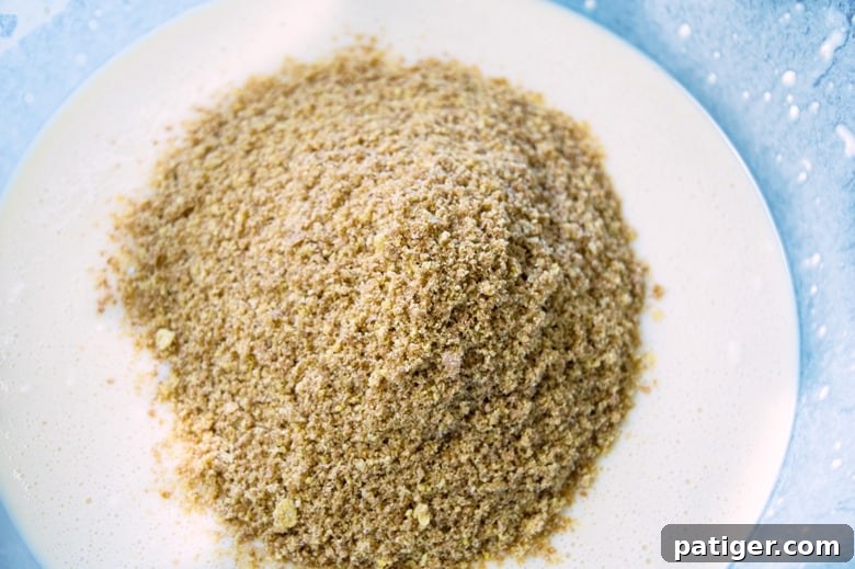 A visual step-by-step image showing dry ingredients being carefully added to wet ingredients in a mixing bowl, illustrating a key stage in the waffle preparation process.