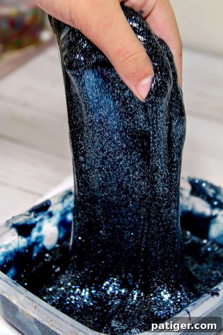 pulling black glittery slime out of clear plastic container