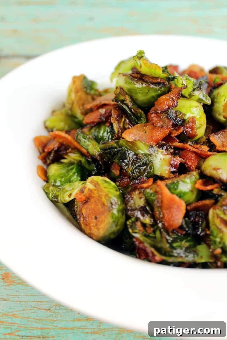 Bacon-Kissed Balsamic Brussels Sprouts 3 A close-up shot of perfectly cooked Brussels sprouts with crispy bacon and a drizzle of balsamic glaze in a white serving bowl.