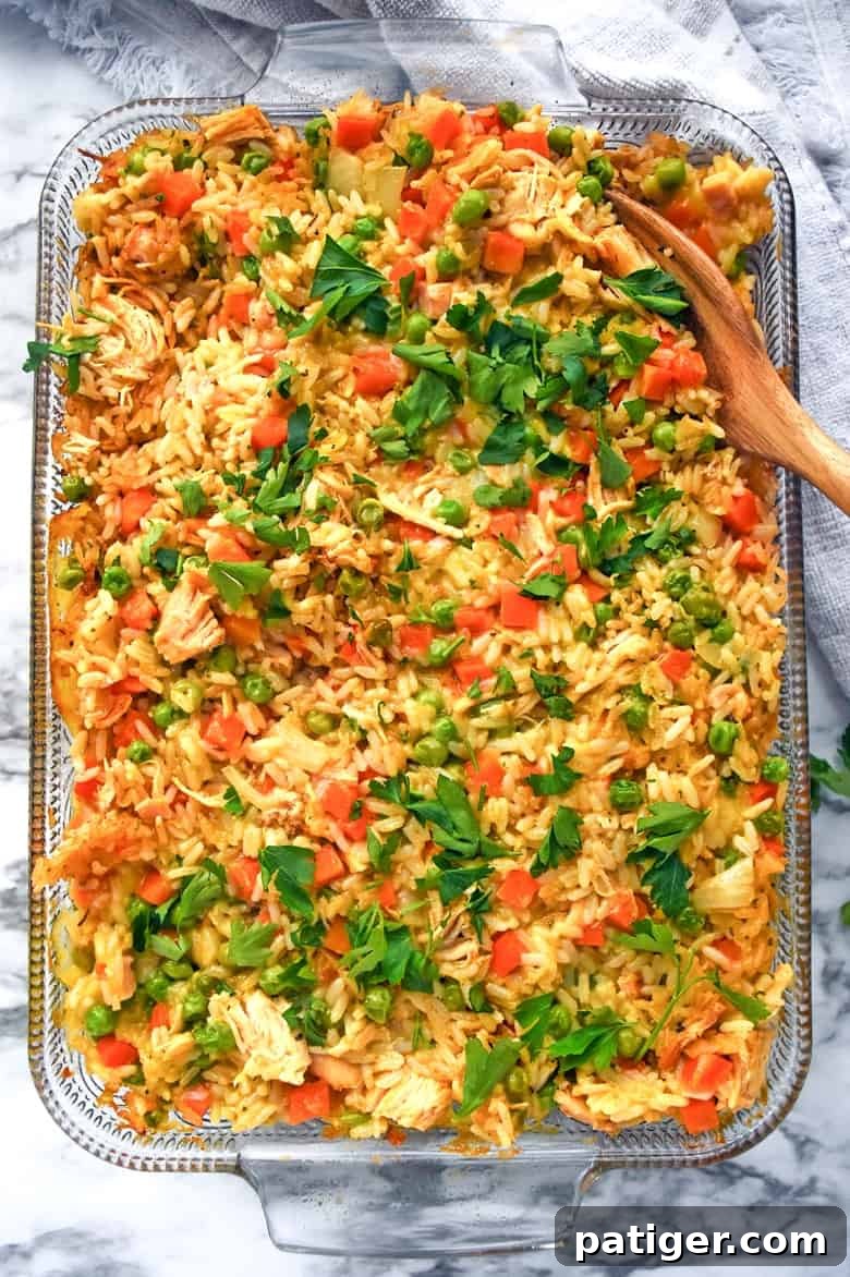 Creamy chicken and rice casserole in baking dish with wooden spoon